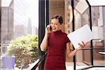 Young white businesswoman on phone looking out office window