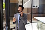 Smiling middle aged Hispanic businessman on phone in office