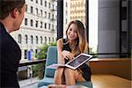 Businessman and woman showing tablet at an office meeting