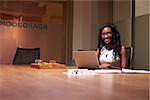 Young black woman working late in office smiling to camera