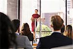Young woman leaning on lectern presenting business seminar