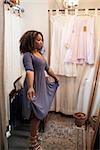 Woman trying on dress in a boutique changing room, vertical