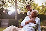 Young black boy embracing grandfather sitting in garden