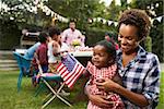 Black mother and baby holding flag at 4th July garden party