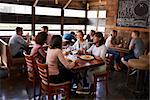 Four female friends at lunch in busy restaurant, full length