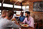 Four male friends at lunch together in restaurant, close up