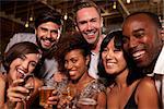 Happy friends at a party in a bar look to camera, close up