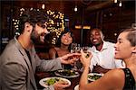 Four friends making a toast over dinner at a restaurant