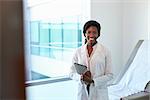 Portrait Of Female Doctor With Digital Tablet In Exam Room