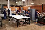 Engineers Working On Machines In Busy Metal Workshop