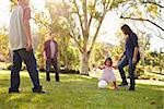 Young mixed race family playing with ball in a park, crop