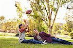 Father and son relax, throwing American football in a park