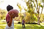 Young boy throwing ball to dad in park, focus on foreground