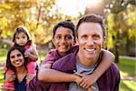 Mixed race parents carry kids piggyback, selective focus