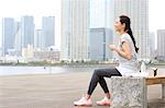 Attractive Japanese woman relaxing after training by a river downtown Tokyo, Japan