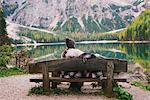 Woman relaxing on park bench, Lago di Braies, Dolomite Alps, Val di Braies, South Tyrol, Italy