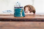 Young boy peering over kitchen work surface, looking at bowl of blueberries