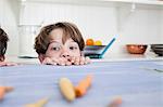 Young boy peering over kitchen work surface