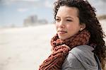 Young woman wrapped in scarf looking out to sea from beach, Western Cape, South Africa