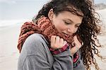 Portrait of young woman wrapped in scarf on windy beach, Western Cape, South Africa