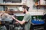 Young male barista preparing coffee in cafe kitchen