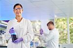 Scientist holding bottle of liquid smiling at camera