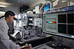 Scientist in laboratory looking through microscope