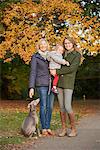 Portrait of senior woman, daughter, granddaughter and dog in autumn park