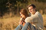 Young couple sitting in rural setting, smiling