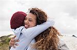 Two young female friends hugging at beach, Western Cape, South Africa