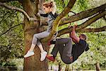 Personal trainer and young woman climbing up park tree