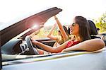 Two young women driving on rural road in convertible, Majorca, Spain