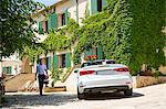 Boutique hotel porter welcoming couple arriving in convertible, Majorca, Spain