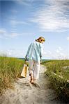 Mature adult woman walking towards the beach.