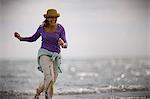 Mid-adult woman playing around in the shallow water of the sea.