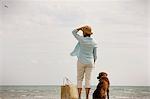 Woman standing on a beach with her dog.