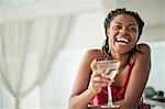 Smiling young woman enjoying a cocktail at a bar.