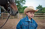 Young boy helping in the horse-training yard at a ranch.