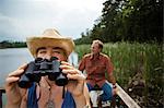 Mature woman takes a break from looking through the binoculars while bird watching at the lake.