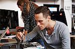 A young man and a young woman working on circuitry in a technology lab.