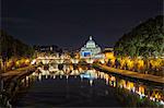 Illuminated St. Peter's Basilica by bridge over river at night, Rome, Italy