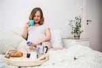 Pregnant woman having breakfast in bed, Munich, Bavaria, Germany