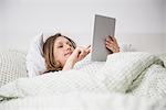 Pregnant woman lying in bed and using digital tablet, Munich, Bavaria, Germany