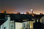 Elevated view of terraced house roof tops and bell tower at night, Brighton, East Sussex, England