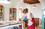 Young woman pouring liquid lavender soap into moulds in handmade soap workshop