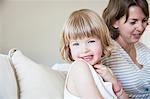 Portrait of cute girl sitting up on bed with mother