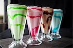 Row of four colourful milkshakes on table