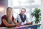 Businessman and woman chatting during coffee break in office