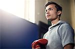 Young male boxer holding boxing gloves in gym