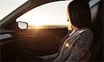 Young woman sitting in passenger seat of car, looking out of window